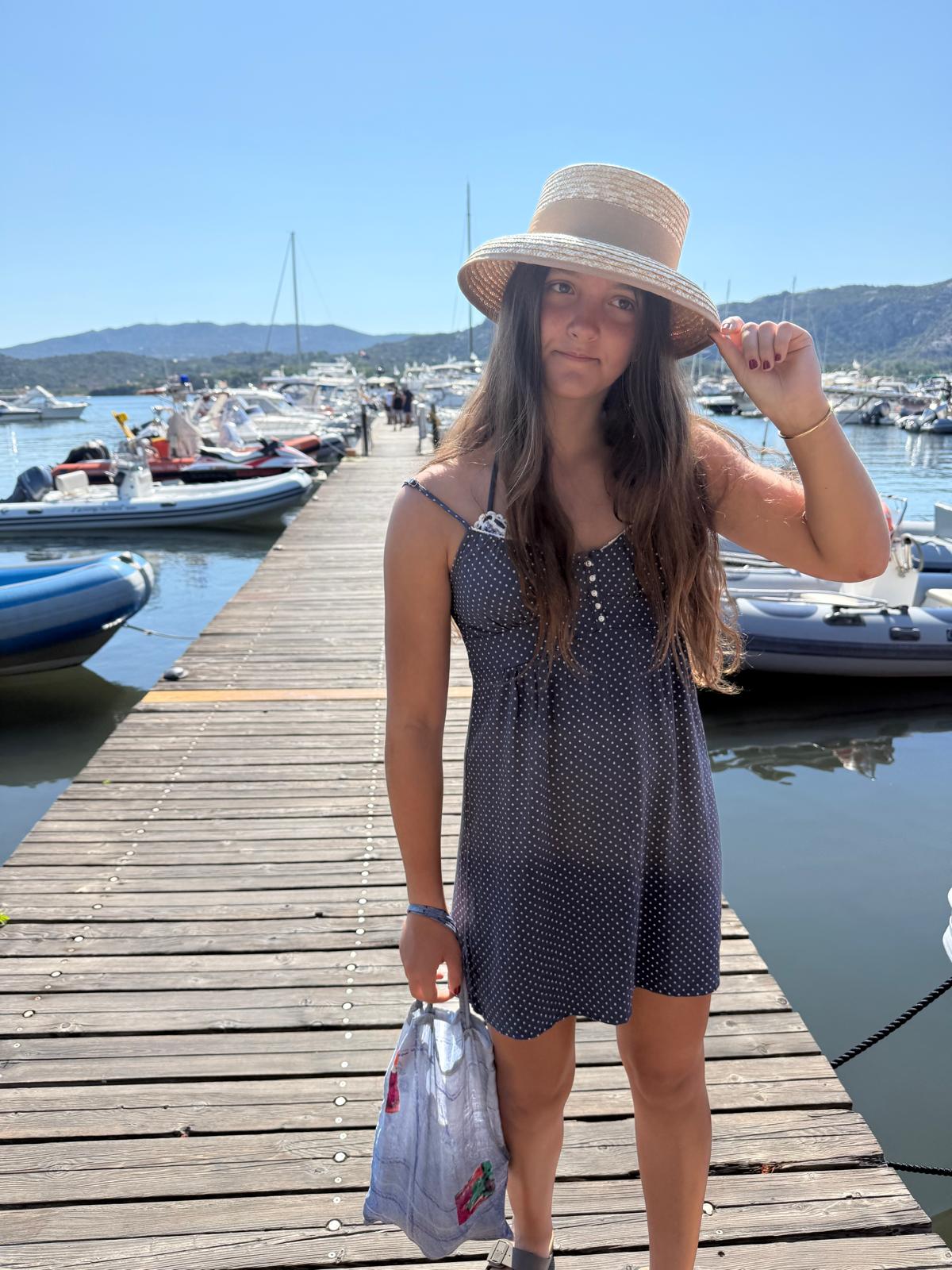 Ruby in a straw hat on a marina jetty in Sardinia