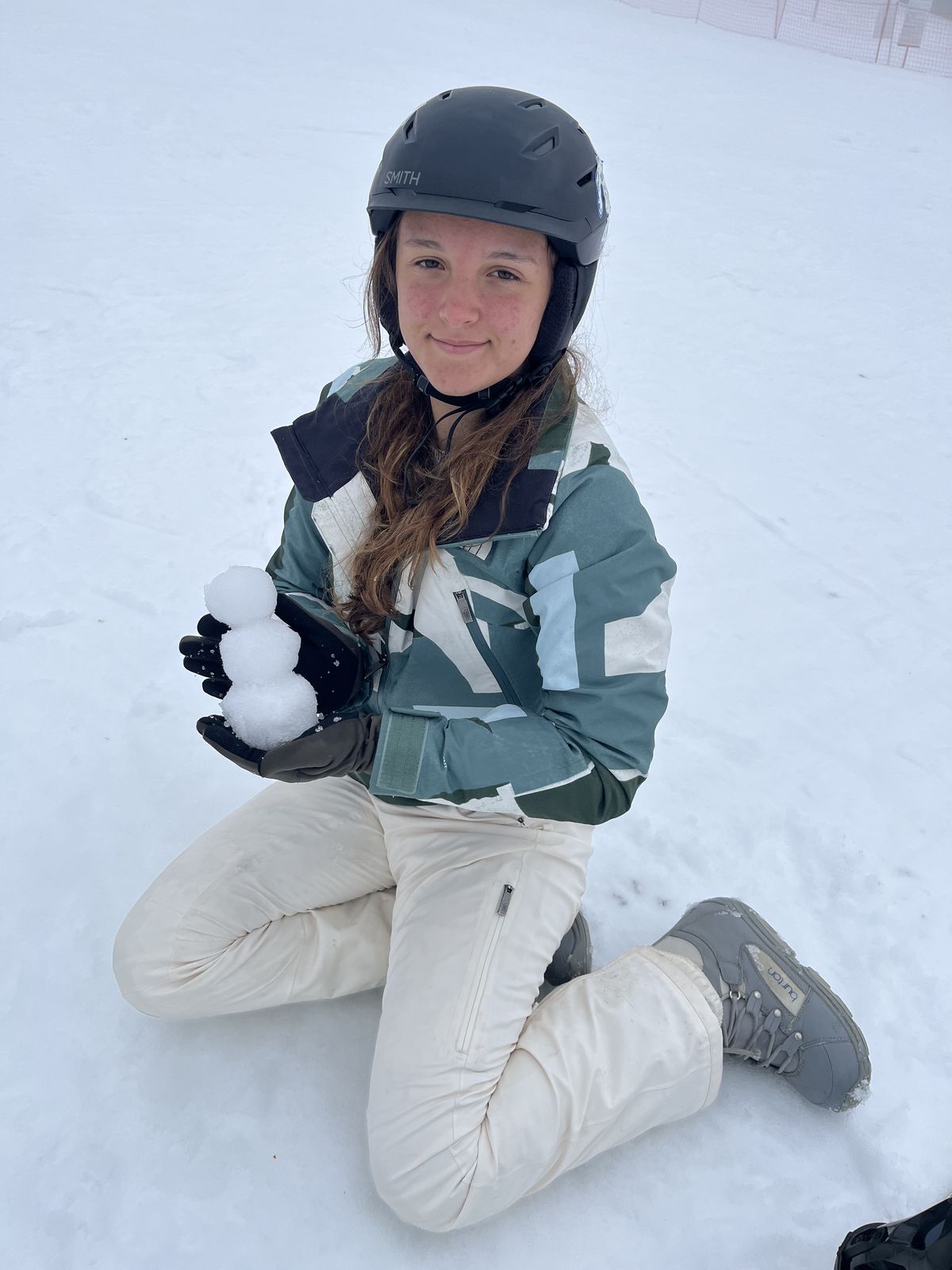 Ruby kneeling in the snow making a snowball