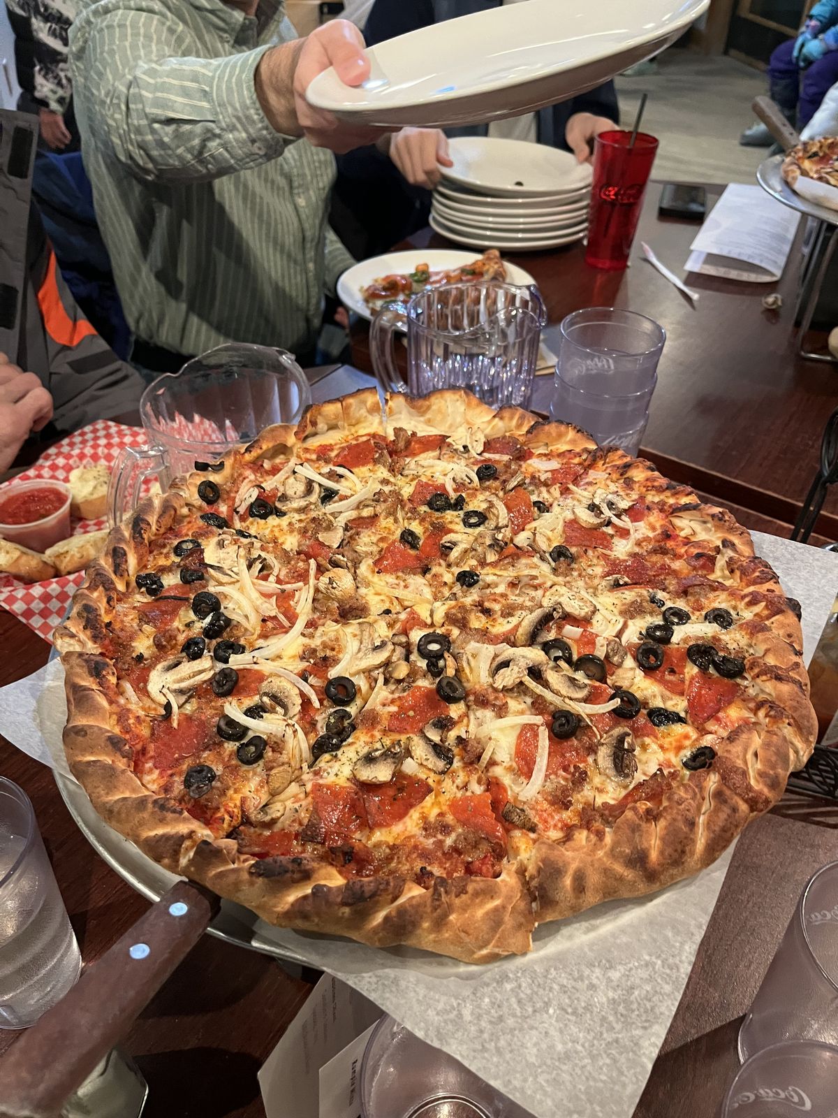 A large pizza arriving at the table